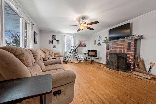 living area with a brick fireplace, crown molding, hardwood / wood-style floors, and ceiling fan