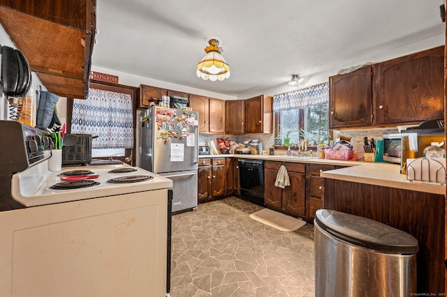 kitchen with black dishwasher, light countertops, electric range, freestanding refrigerator, and a sink