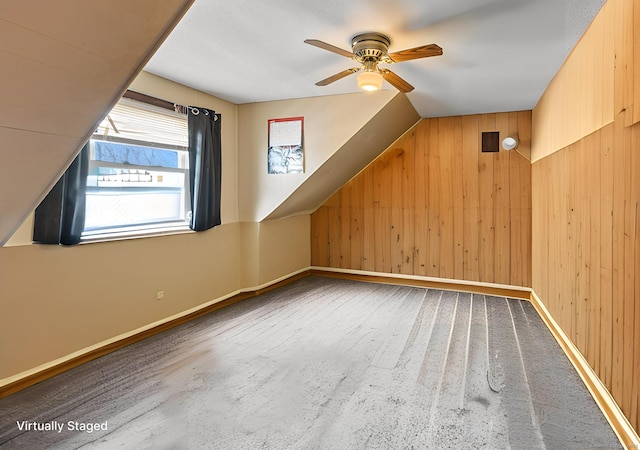 additional living space with wood walls, a ceiling fan, and baseboards