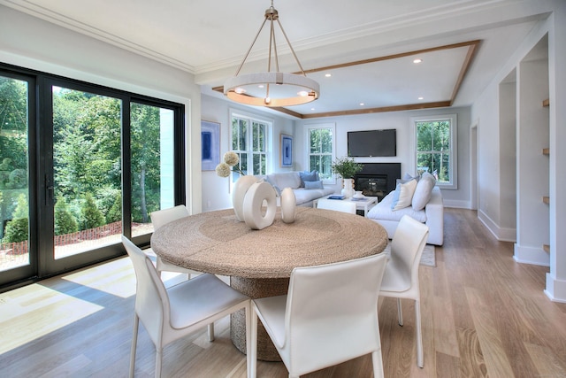 dining space featuring recessed lighting, baseboards, light wood-style floors, a glass covered fireplace, and crown molding