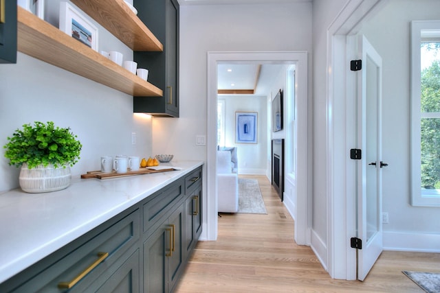 interior space with light countertops, light wood finished floors, open shelves, and gray cabinetry