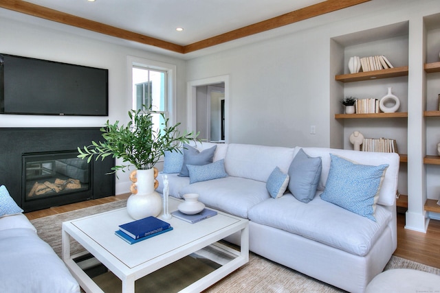 living room featuring built in shelves, a glass covered fireplace, recessed lighting, and wood finished floors