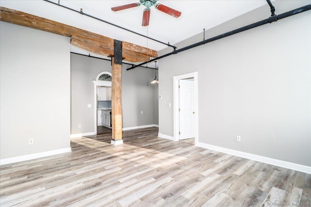 interior space with a barn door, light wood-type flooring, a ceiling fan, and baseboards