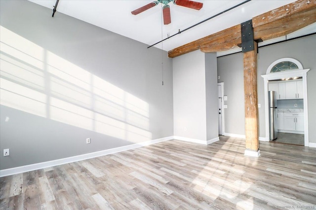 unfurnished room with a ceiling fan, light wood-style flooring, and baseboards