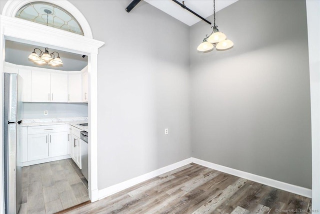 kitchen with white cabinets, light countertops, freestanding refrigerator, an inviting chandelier, and pendant lighting