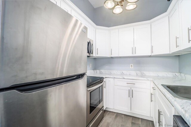 kitchen featuring stainless steel appliances, light wood-type flooring, light stone countertops, and white cabinets