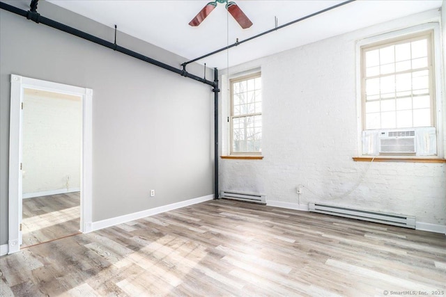 empty room featuring ceiling fan, light wood finished floors, baseboard heating, and baseboards