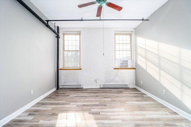 spare room featuring a wealth of natural light, a baseboard radiator, and light wood-style flooring