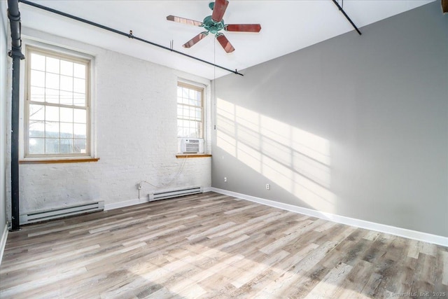 empty room with light wood-type flooring, a baseboard radiator, and a healthy amount of sunlight