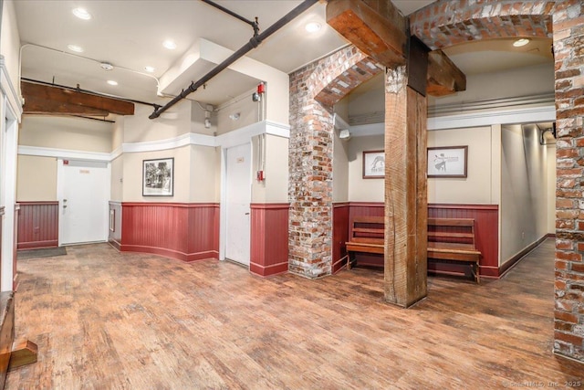 spare room featuring a wainscoted wall, wood finished floors, and ornate columns