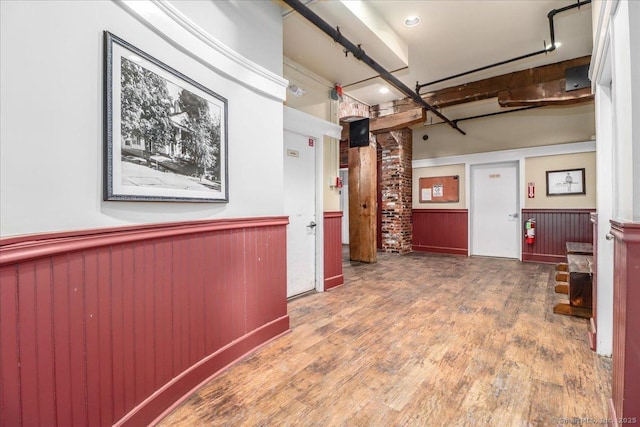 hall with a wainscoted wall and wood finished floors