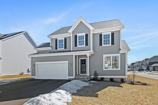 view of front of home with driveway, a shingled roof, and a garage