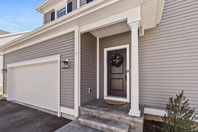 view of exterior entry with a garage and aphalt driveway