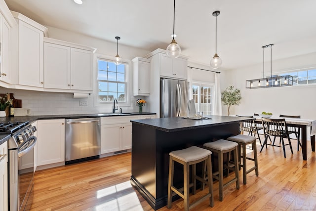 kitchen featuring appliances with stainless steel finishes, dark countertops, backsplash, and a healthy amount of sunlight