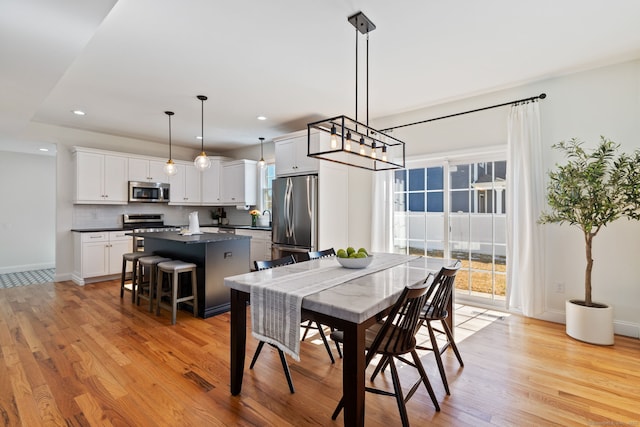 dining room featuring baseboards, light wood-type flooring, visible vents, and recessed lighting