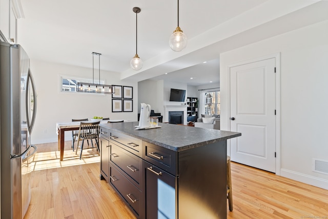 kitchen with dark countertops, light wood-type flooring, a fireplace, and freestanding refrigerator