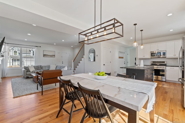 dining room featuring light wood-type flooring, stairs, and recessed lighting