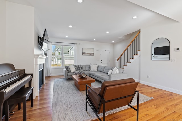 living area with recessed lighting, a fireplace, wood finished floors, baseboards, and stairway