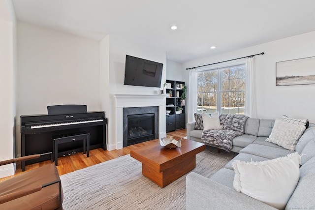 living area with a glass covered fireplace, recessed lighting, and wood finished floors