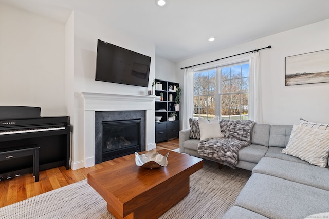 living area featuring a glass covered fireplace, recessed lighting, and wood finished floors