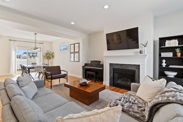 living room with baseboards, a glass covered fireplace, wood finished floors, and recessed lighting