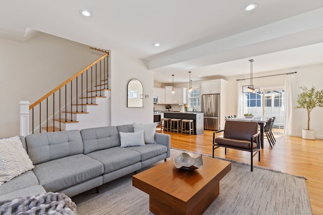 living room featuring stairs, light wood finished floors, a chandelier, and recessed lighting