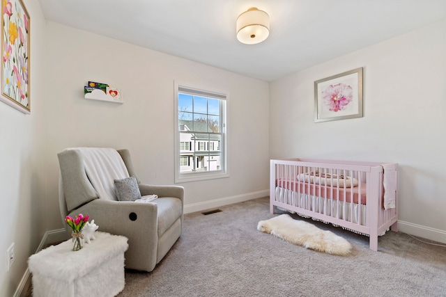 carpeted bedroom featuring a crib, visible vents, and baseboards