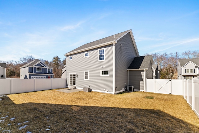 back of property featuring a gate, a fenced backyard, a yard, and central AC