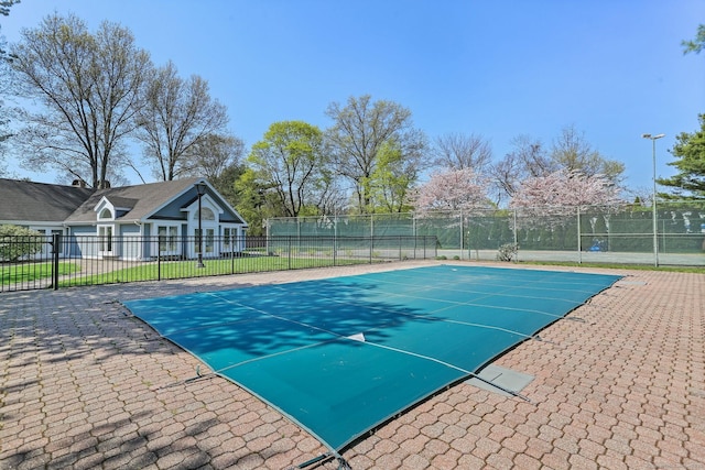 view of swimming pool featuring fence and a tennis court