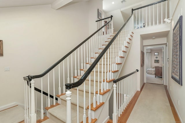 stairs with baseboards, a high ceiling, carpet floors, and visible vents