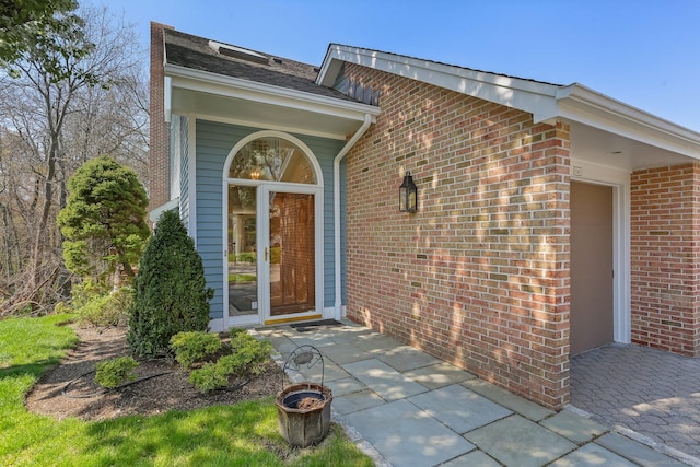 view of exterior entry featuring an attached garage and brick siding