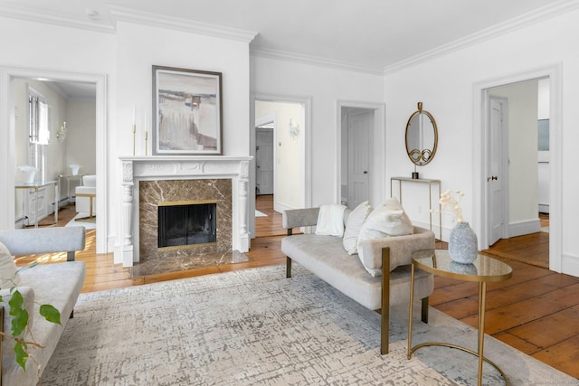 living room featuring ornamental molding, a high end fireplace, light wood-style flooring, and baseboards