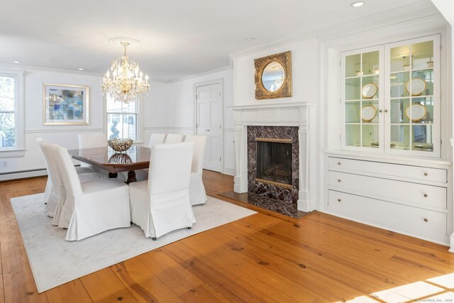 unfurnished dining area with a fireplace, crown molding, recessed lighting, a chandelier, and light wood-type flooring