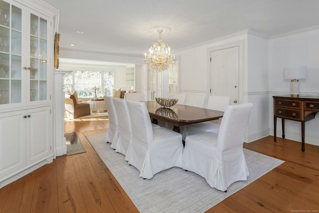 dining area featuring ornamental molding, light wood-type flooring, and a notable chandelier