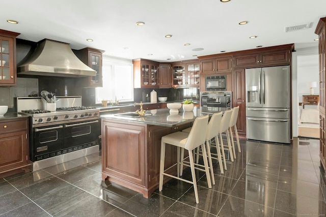 kitchen with a center island, stainless steel appliances, granite finish floor, glass insert cabinets, and wall chimney range hood