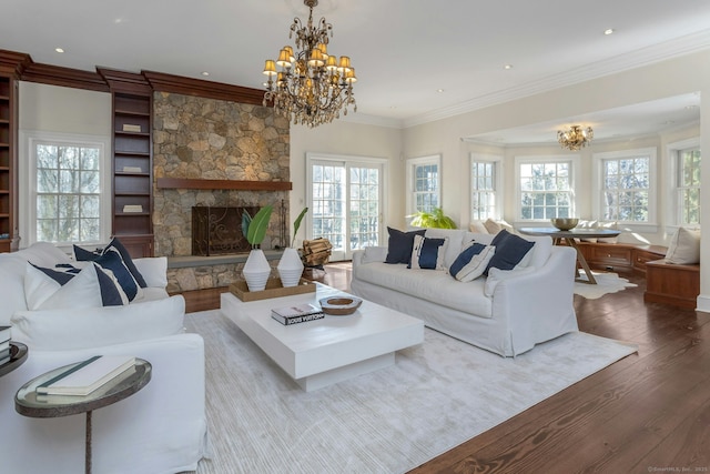 living area with ornamental molding, a healthy amount of sunlight, wood finished floors, and a notable chandelier