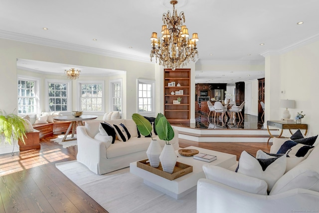 living area featuring ornamental molding, light wood-type flooring, and an inviting chandelier