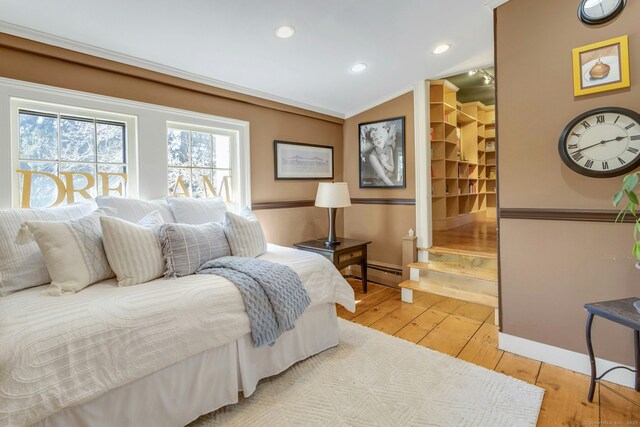 bedroom with lofted ceiling, recessed lighting, baseboard heating, ornamental molding, and wood finished floors