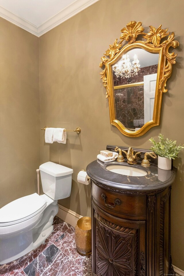 half bathroom featuring ornamental molding, baseboards, vanity, and toilet