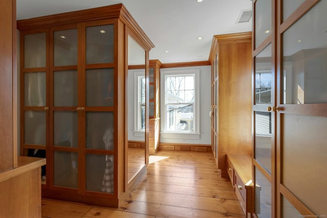 doorway to outside with light wood-style flooring, visible vents, and crown molding