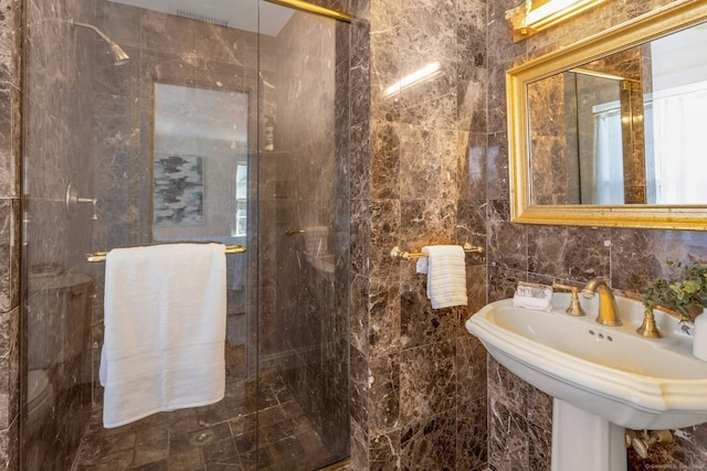 full bath with a stall shower, a sink, and tile walls