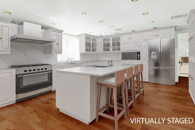 342 Greens Farms Rd, Westport, CT 06880 - kitchen with wall chimney range hood, light wood-style flooring, visible vents, stainless steel appliances, and a sink