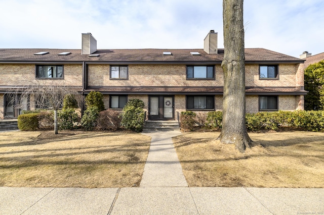 townhome / multi-family property with brick siding and a chimney