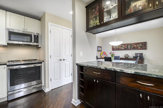 kitchen featuring tasteful backsplash, glass insert cabinets, dark stone countertops, stainless steel appliances, and white cabinetry