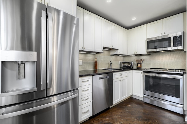 kitchen with dark wood finished floors, stainless steel appliances, backsplash, white cabinets, and a sink