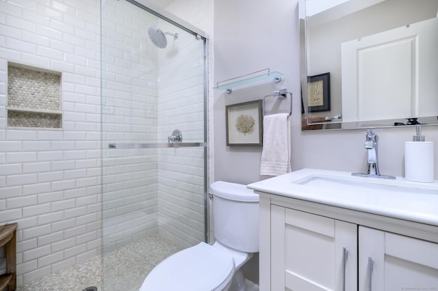 full bath featuring toilet, a tile shower, and vanity