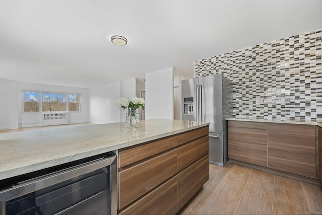 kitchen with wine cooler, brown cabinets, high end fridge, modern cabinets, and light wood-type flooring