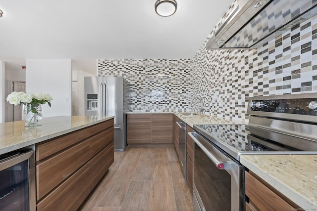 kitchen featuring beverage cooler, a sink, appliances with stainless steel finishes, light wood-type flooring, and backsplash