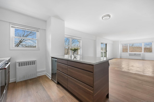 interior space with beverage cooler, light wood-style floors, and radiator