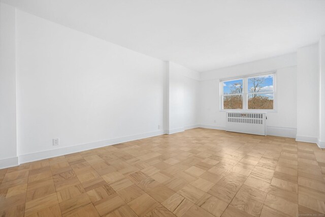 empty room featuring baseboards and radiator heating unit